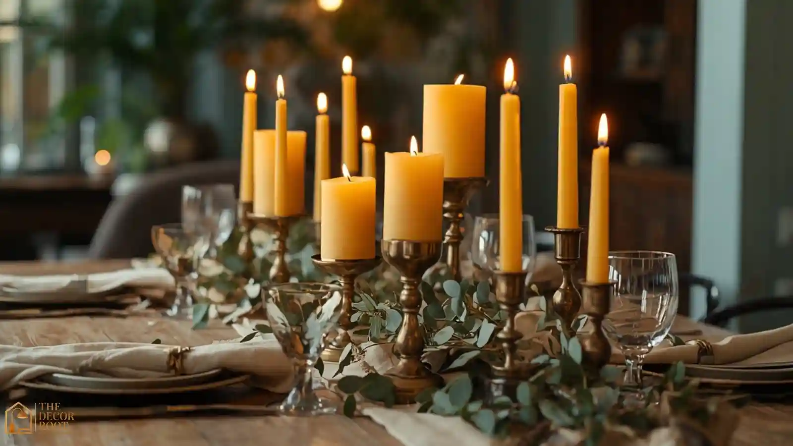 A holiday dining table with brass candle holders, dried eucalyptus, and cream linen napkins in a boho style