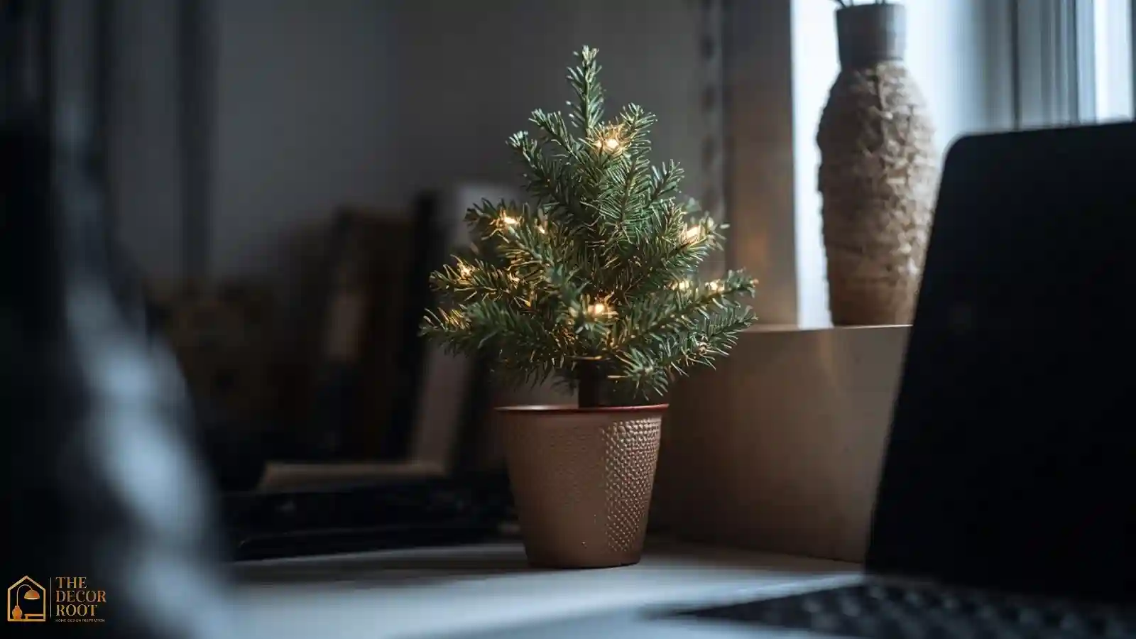 A small potted pine tree with subtle white lights sitting on the corner of a tidy office desk